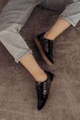 Zapatillas bajas color beige con estampado de piel de serpiente metalizada, cordones blancos y suela color caramelo.