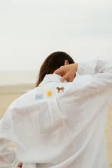 Camisa negra de lino con cuello clásico, manga larga y cierre frontal con botones. Presenta un bordado con un caballito, un sol y la bandera de Uruguay en el frente.