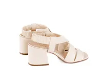 Sandalia de cuero color blanco hueso, con tiras cruzadas acolchadas, talón elástico fruncido, taco ancho de 6 cm y punta cuadrada.