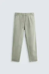Pantalón color arena de corte recto, confeccionado en tejido de algodón y lino. Cuenta con cintura elástica ajustable con cordón, bolsillos delanteros y traseros de parche.