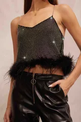 Top musculosa negro con brillos plateados, tirantes de cadena y detalle de plumas en el ruedo.