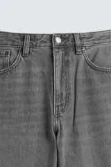 Jeans de denim de algodón, color negro lavado, con tiro medio, corte ajustado en cadera y muslos, y pierna que se estrecha hacia el tobillo. Presenta cinco bolsillos y cierre frontal con cremallera y botón.