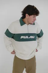 Buzo color crema con cuello polo, cierre de cremallera corto y banda horizontal verde con la palabra 'Pulau' estampada en blanco.