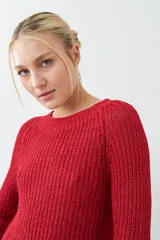Sweater rojo de tejido de punto con ruedo curvo y mangas 3/4.