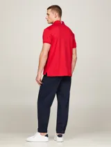 Chomba Tommy Hilfiger Essential de corte regular, color rojo, confeccionada en algodón. Presenta cuello tipo polo, cartera de dos botones y logo bordado en el pecho.