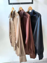 Camisa marrón de satén con cuello clásico, cierre frontal con botones y mangas largas con puños abotonados.