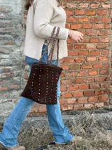 Cartera tipo tote bag de cuero color marrón chocolate, con apliques de cuentas de colores y asas trenzadas.