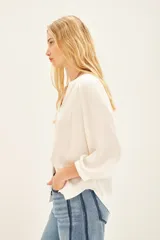 Camisa blanca de poliéster con cuello mao y mangas largas con frunces en hombros, mangas y espalda.