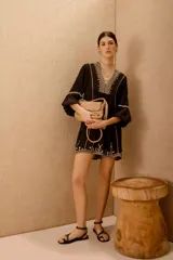 Vestido corto negro con bordado de hilo blanco, escote en V y mangas largas abullonadas.