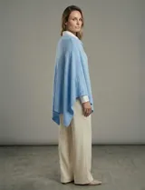 Poncho tejido de punto grueso, color mostaza/mostaza oscuro, con cuello redondo y caída amplia.