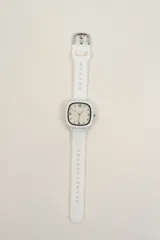 Reloj de pulsera blanco con caja cuadrada y correa de silicona con hebilla metálica.