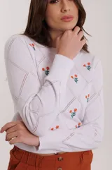 Sweater blanco de tejido de punto calado con diseño de rombos y flores bordadas en color naranja y verde.