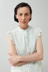 Camisa sin mangas color verde agua con cuello mao, cierre frontal con botones y detalle de puntilla en los hombros.