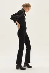 Jean negro de tiro medio con silueta levemente acampanada desde la rodilla.