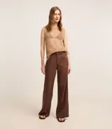 Pantalón wide leg color marrón chocolate, confeccionado en sarga de algodón y lyocell, con cintura alta, trabillas, cierre con botón y cremallera, y bolsillos tipo carpintero. Presenta botones color carey en los bolsillos delanteros.