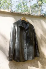 Camisa negra de cuero napa, con cuello clásico, cierre frontal con botones, manga larga y bolsillo de parche en el pecho.