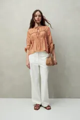 Blusa estampada celeste y blanca de caída fluida con cuello redondo y lazos frontales. Diseño con cortes horizontales y frunces, mangas largas con puños elastizados.