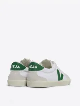 Zapatillas bajas blancas con logo en forma de V verde en el lateral.