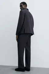 Pantalón de vestir negro de corte relaxed fit confeccionado en tejido con lana. Cuenta con bolsillos frontales y traseros de doble vivo con botón. Cierre frontal con cremallera y botón.