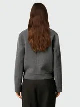 Chaqueta corta gris de lana con corte cuadrado, cuello clásico, cierre abotonado y bolsillos de parche.