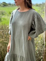 Vestido largo color beige, de corte amplio, con mangas cortas abullonadas y volado en el ruedo.