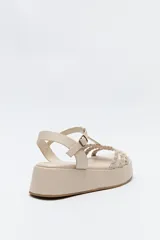 Sandalia de plataforma color marrón con tiras trenzadas y pulsera con hebilla.