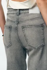 Pantalón de jean azul de tiro alto, corte mom fit, tobillero y con cinco bolsillos. Cierre frontal con cremallera y botón.
