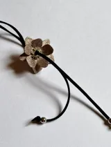 Gargantilla choker de terciopelo negro con dije de flor dorada con glitter.