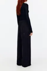 Pantalón palazzo negro de terciopelo con estampado floral, corte culotte, cintura elástica y bolsillos laterales.