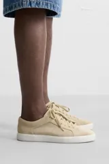 Zapatillas bajas color beige de gamuza, con cordones y suela blanca.