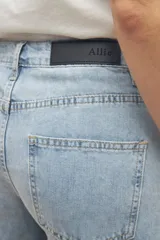 Pantalón de jean negro de corte ancho, tiro medio y cinco bolsillos.
