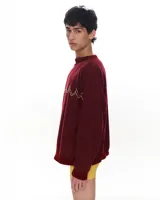 Sweater color borgoña con bordado de líneas en zigzag color dorado en el pecho. Tejido de lana, algodón y viscosa, con terminaciones de cuello y puños a mano.