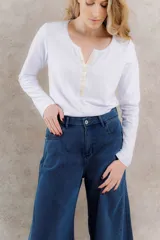 Remera blanca de algodón con mangas largas y cuello redondo con cartera de lino color crema con botones al tono.