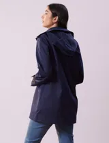 Gabardina impermeable color beige, marca Weatherproof, con abertura central con botones, bolsillos delanteros y capucha desmontable.