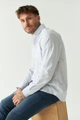 Camisa celeste a rayas rojas de hombre, manga larga, con bolsillo y logo bordado.