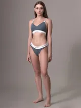 Conjunto Calvin Klein de ropa interior, compuesto por un corpiño deportivo gris con elástico blanco con logo de la marca y una tanga gris con elástico blanco con logo de la marca.