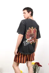 Remera negra de algodón con estampa de un girasol y texto en la espalda. Corte clásico y mangas cortas.