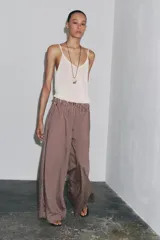 Pantalón de tiro medio con cintura elástica y bolsillos laterales ocultos en costura. Pierna ancha y estampado a rayas verticales color borgoña y blanco.