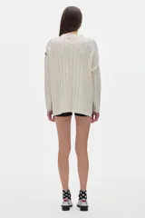 Sweater tejido color borgoña con cuello alto, corte oversize y mangas largas con detalle de trenzas verticales.