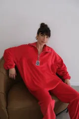Buzo rojo de plush terciopelo con cierre parcial frontal y detalle de etiqueta con logo en el pecho.