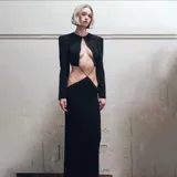 Vestido largo negro con escote redondo, mangas largas y aberturas laterales en la cintura.