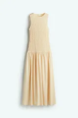 Vestido largo color crema, sin mangas, con cuerpo fruncido y falda con leve vuelo.