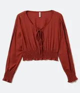 Blusa color ladrillo con escote redondo con ajuste, mangas largas con aberturas en los hombros y elástico en la cintura.