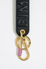 Llavero de cinta de piel color beige claro con logo en relieve y forro interior color azul eléctrico. Incluye mosquetón y anilla metálicos.