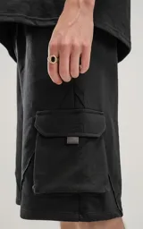 Bermuda negra de algodón rústico con calce oversize, elástico en la cintura y bolsillos con cierre.