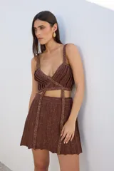 Top negro con lurex, de breteles finos y corte irregular con tiras cruzadas en el abdomen.