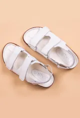 Sandalias bajas de cuero color rosa claro, con suela de corcho y ajuste con velcro.