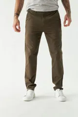 Pantalón chino color beige, de corte slim, con bolsillos laterales y traseros. Se ajusta a la cintura con cinturón de cuero marrón.