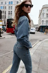 Pantalón de jean azul de tiro alto, corte mom fit, tobillero y con cinco bolsillos. Cierre frontal con cremallera y botón.