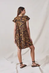 Vestido midi de viscosa con estampado floral en tonos ocre sobre fondo negro. Tiene corte evasé, mangas cortas con volados y largo hasta la rodilla.